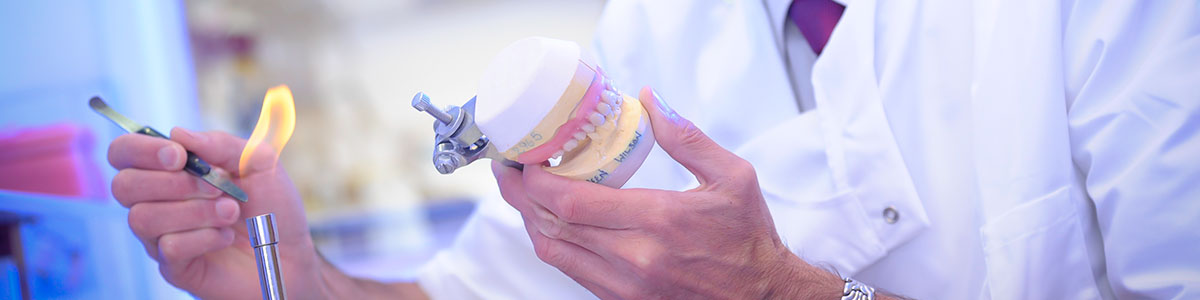 Dental technician finishing dental restoration with articulator